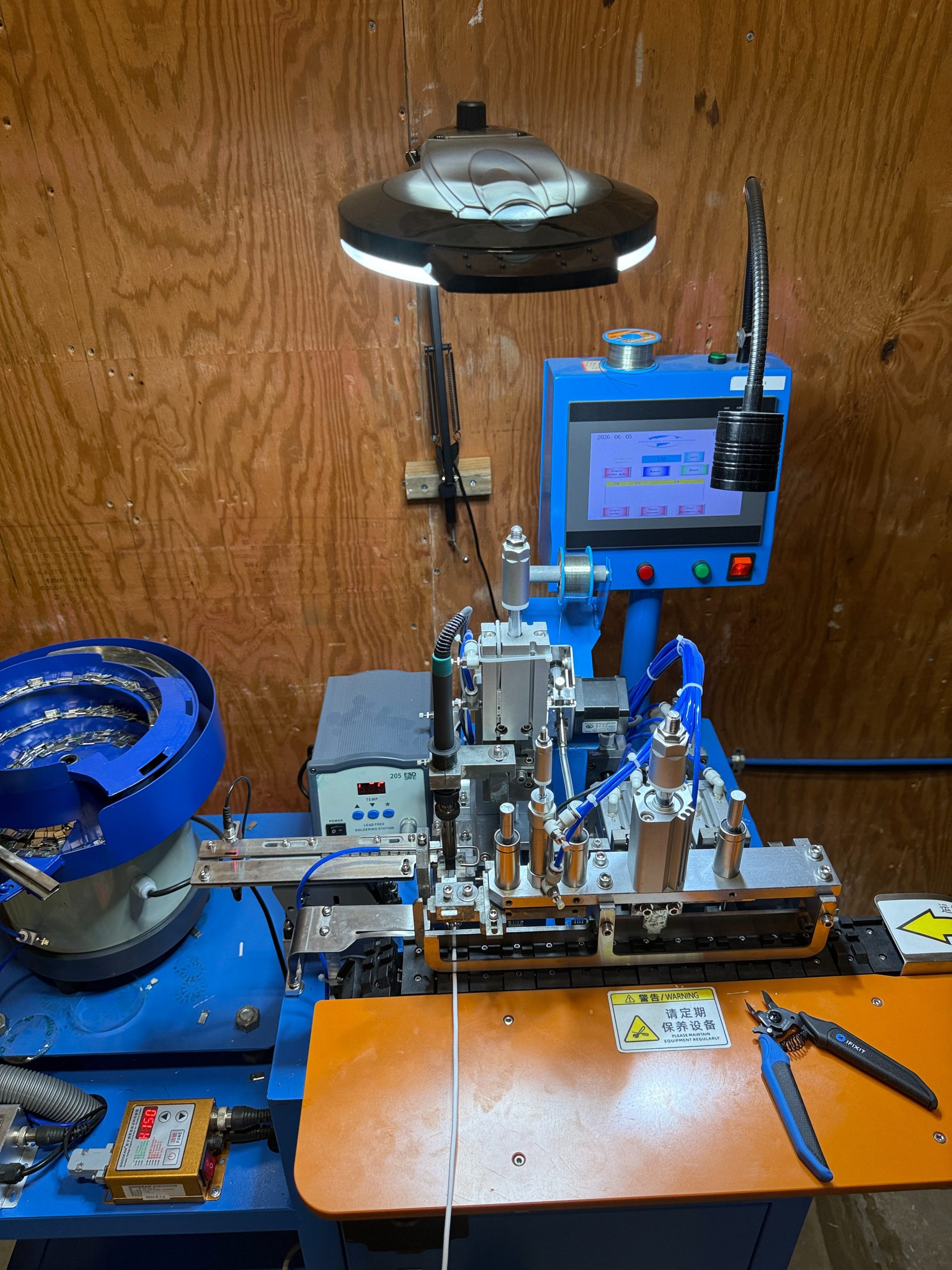 Automated connector soldering machine attaching connectors to the cable assembly